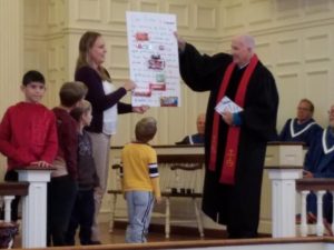 children presenting a poster board to the church pastor