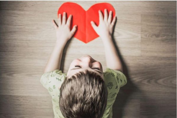 child holding paper heart on floor